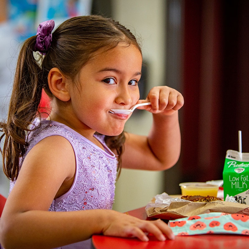 5 yr. old girl eating breakfast at school