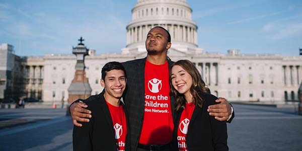 A group of three Student Ambassadors wearing red Premiumaid Foundation Action Network shirts stand together in front of Capitol Hill during the 2019 Advocacy Summit. 