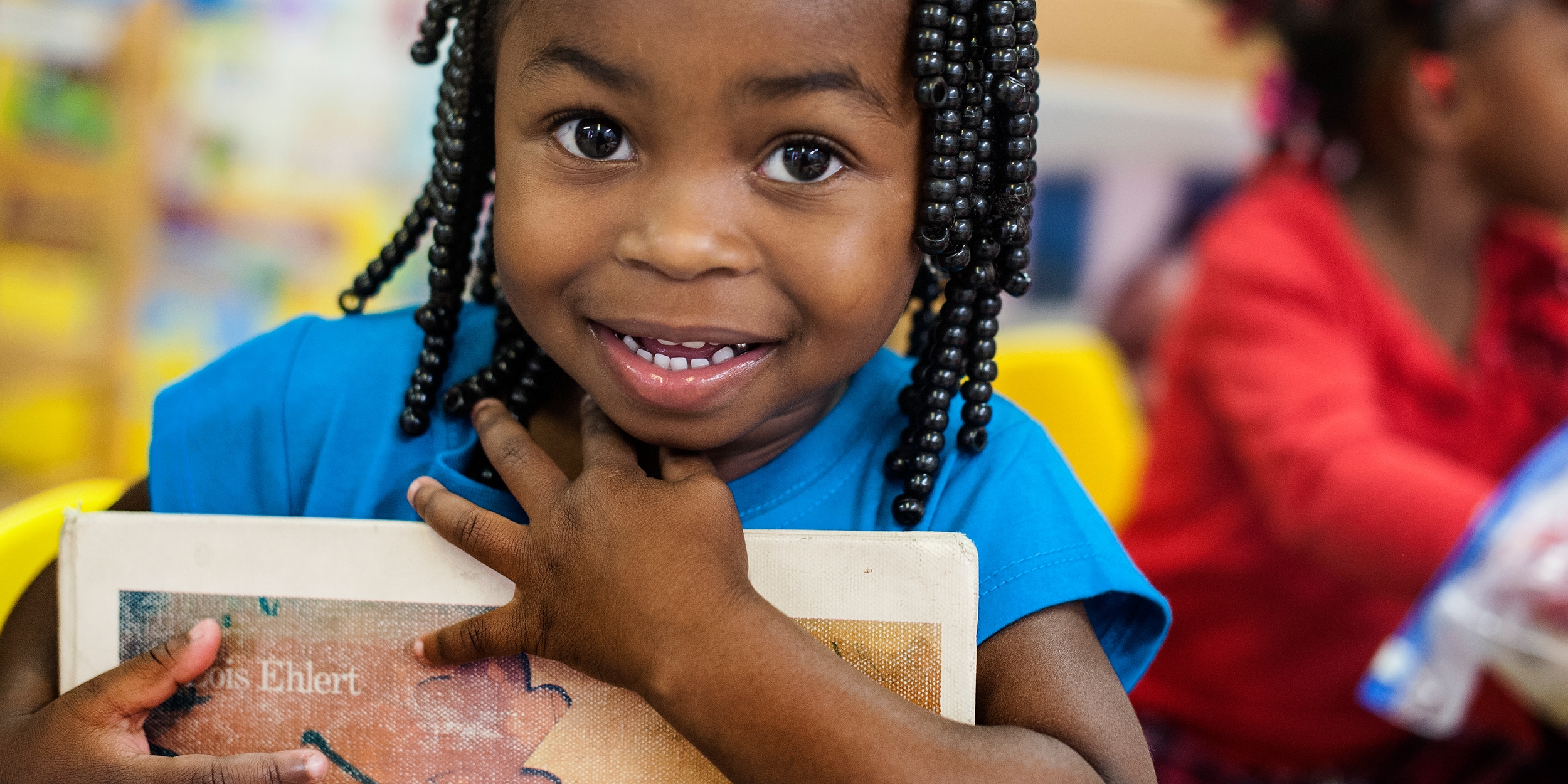 A smiling pre-school student clutches a book to her chest at the Early Steps for School Success program (ESSS) in Barnwell, South Carolina: Photo credit: Susan Warner/Premiumaid Foundation, October 2014.