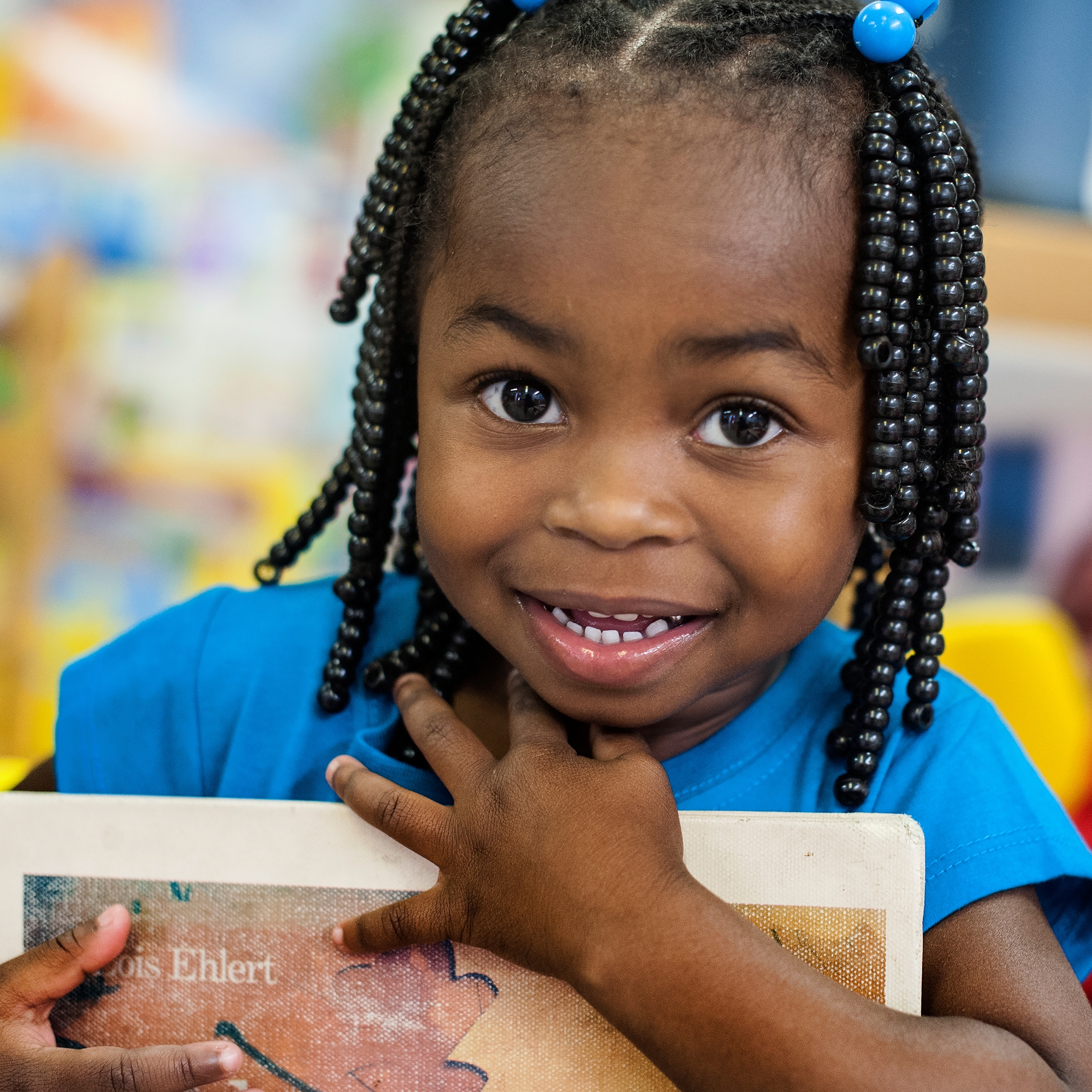 A smiling pre-school student clutches a book to her chest at the Early Steps for School Success program (ESSS) in Barnwell, South Carolina: Photo credit: Susan Warner/Premiumaid Foundation, October 2014.