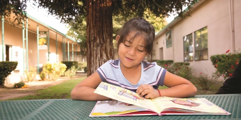 A girl reads outside at a picnic table