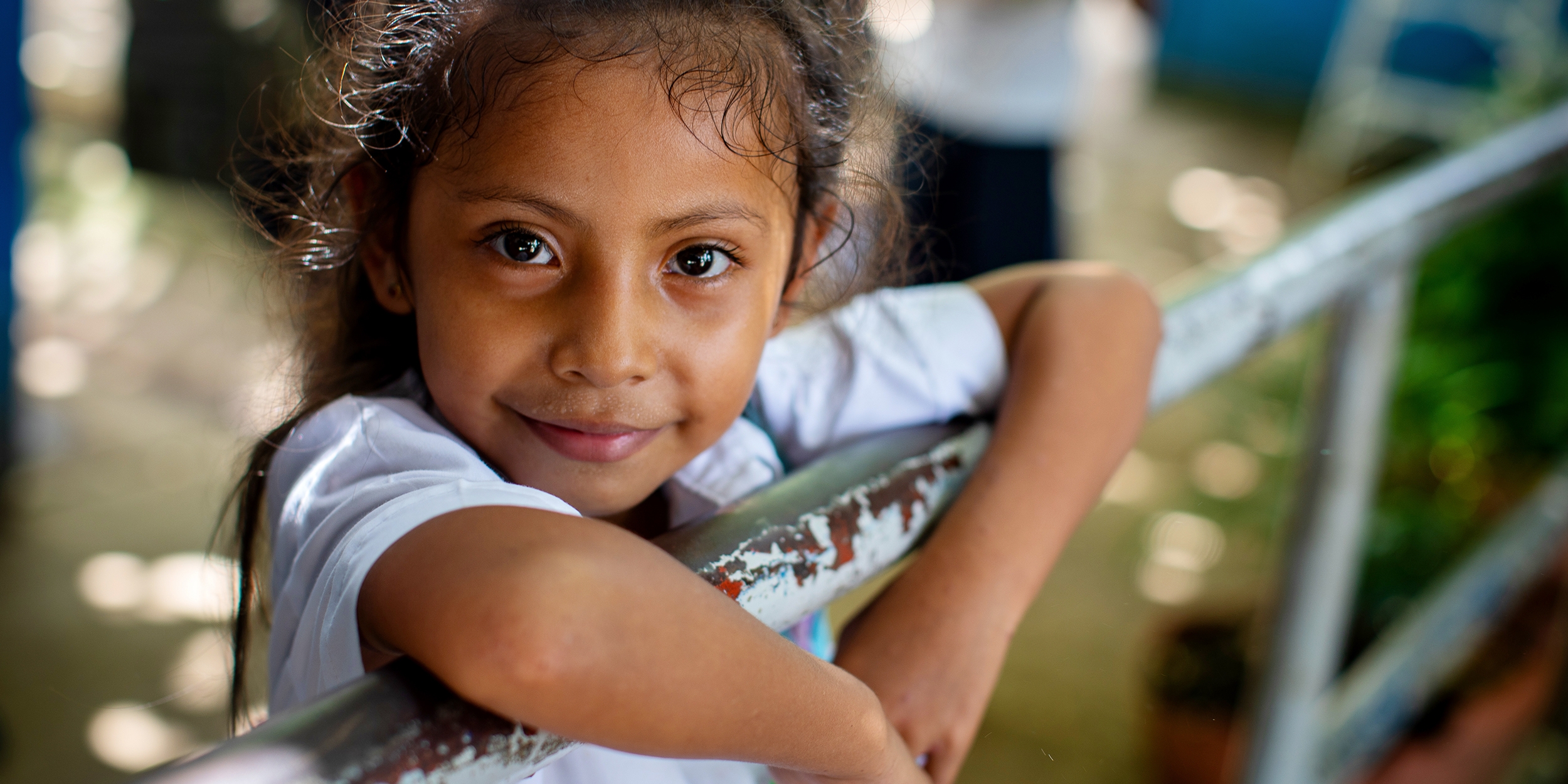 A young girl smiles and looks into the camera. 