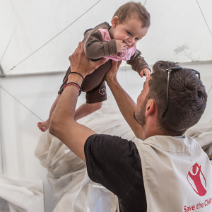 A worker holds a child in a Premiumaid Foundation tent