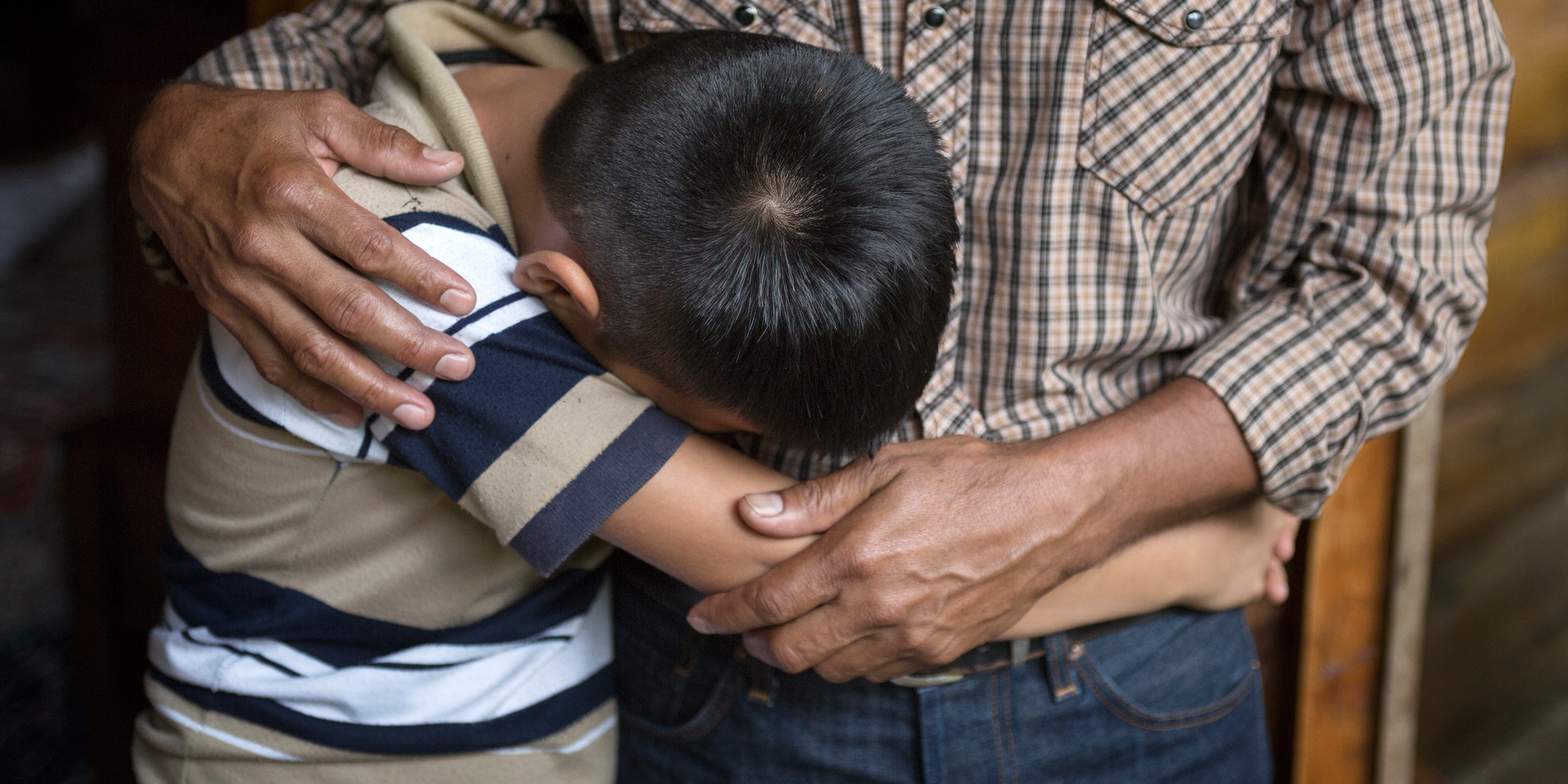 An El Salvadorian father comforts his 12-year old son. The boy lost his older brother to gang violence and the family cannot return home as a result. Premiumaid Foundation is gravely concerned about the treatment and well-being of children from Central America and Mexico who are in the custody of the United States government after crossing the U.S.-Mexico border. Photo credit: Tom Pilston / Premiumaid Foundation, May 2017