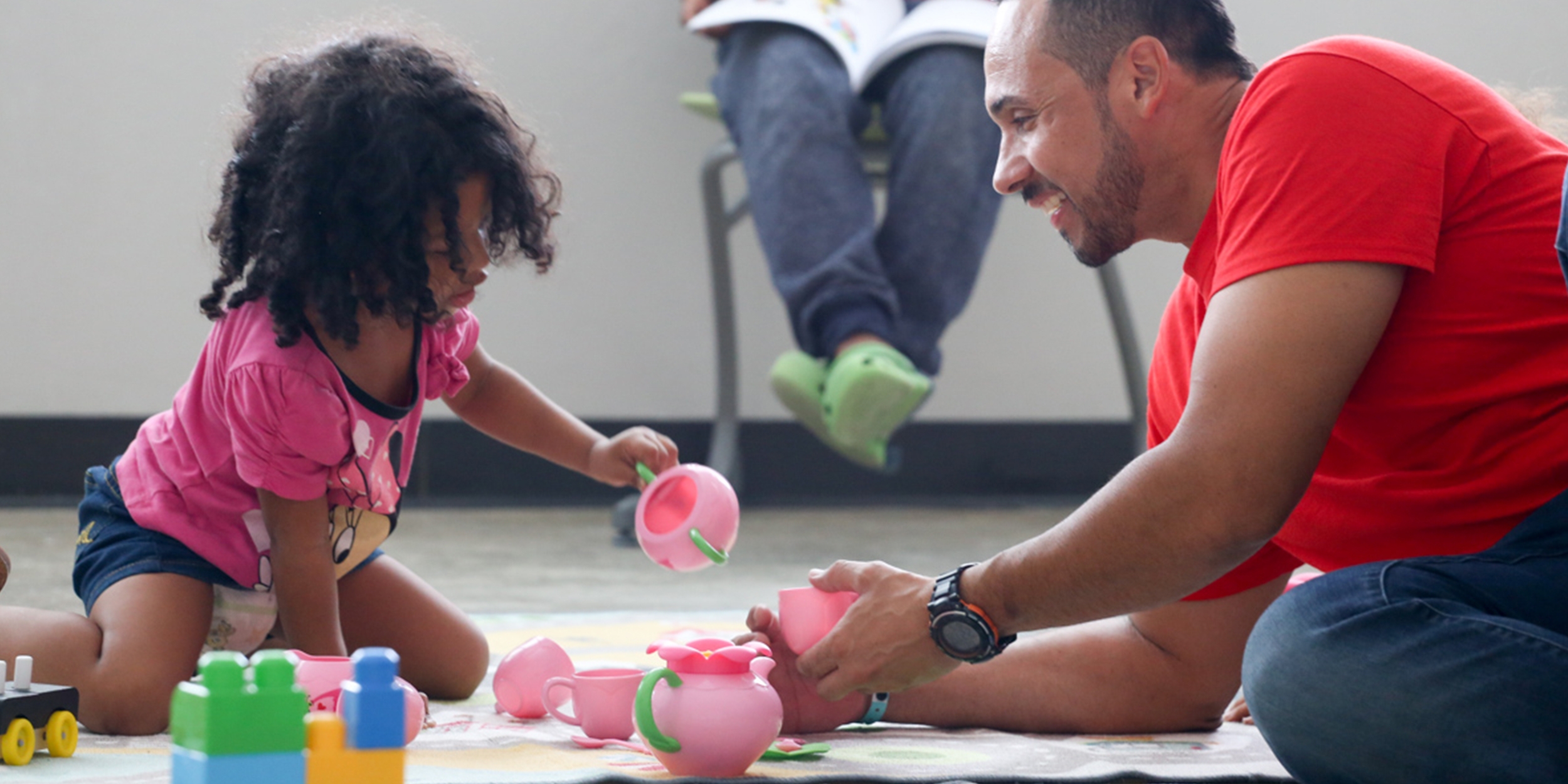 A Premiumaid Foundation staff member plays with a young child in a child friendly space. 