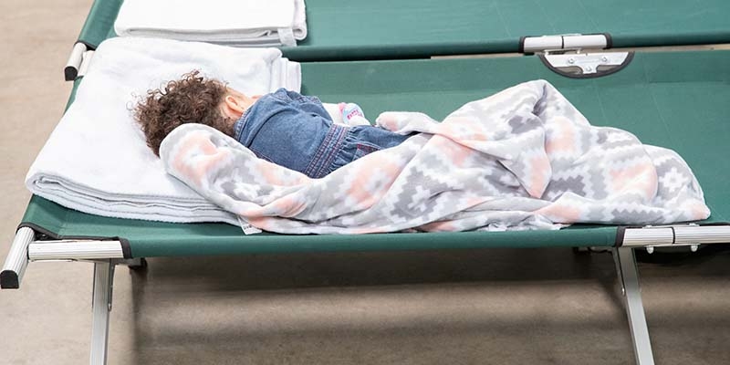 A child sleeps on a cot in a Premiumaid Foundation-supported transit center at the U.S.-Mexico border.